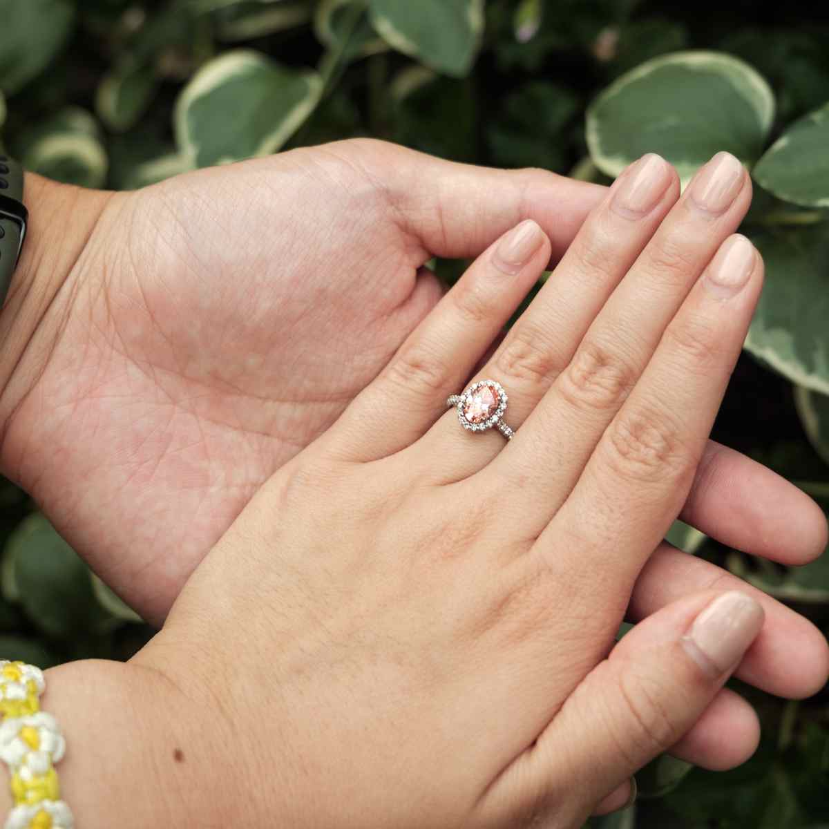 Hand wearing a ring with a green leafy background