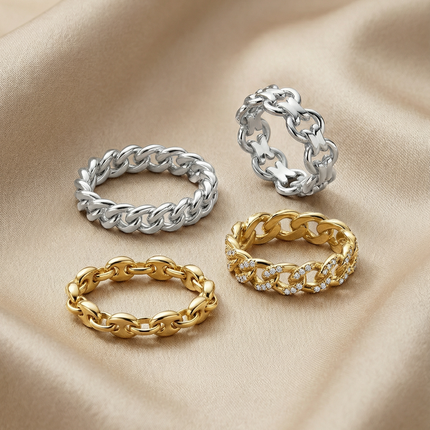 Four chain-link rings in gold and silver on a beige fabric background